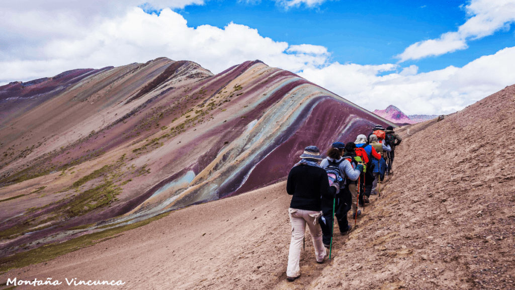 Group of tourists hiking to Rainbow Mountain on a sunny day
