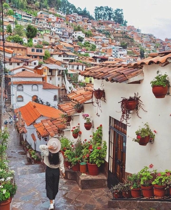 Cusco – woman walking along a traditional street with balconies and colonial rooftops